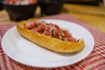 Traditional Mexican mollete on a plate above white and red checkered napkin