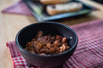 Chopped pork in black bowl above checkered napkin