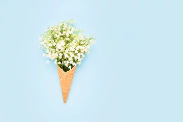 Foto auf Leinwand Lily-of-the-valley bouquet in waffle ice cream cone on a blue background © Laima
