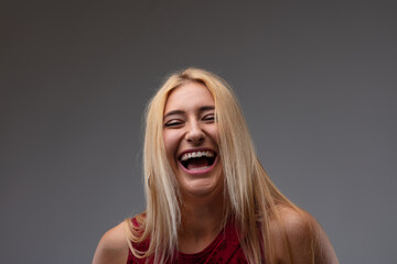 Carefree vivacious blond woman laughing at the camera - obrazy, fototapety, plakaty