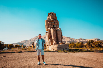 Tourist man near  Colossus of Memnon in Luxor. Big statues near the Valley of Kings. Egypt