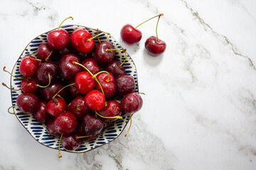 Top view of fresh cherries on bowl on marble background with copy space