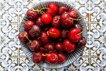 Top view of cherries bowl on portuguese tiles background