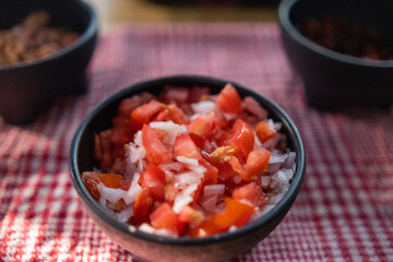 Black bowls of pico de gallo above checkered tablecloth