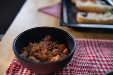 Chopped pork in black bowl above checkered napkin