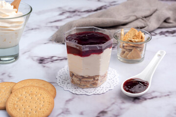 sweet desserts chocotorta and chiskey with cookies sweet milk and red fruit jam in glasses on light marble countertops