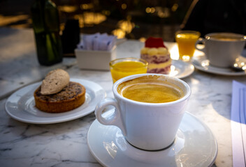 Close-up of cup of coffee with cinnamon dessert behind served at breakfast.