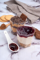 sweet desserts chocotorta and chiskey with cookies sweet milk and red fruit jam in glasses on light marble countertops