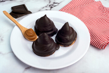Chocolate covered dulce de leche glasses with a glass open in half on the counter and squared napkin