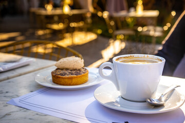 Close-up of cup of coffee with cinnamon dessert behind.