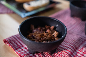 Chopped pork in black bowl above checkered napkin