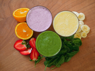 Three healthy smoothies with fruit garnish on the side