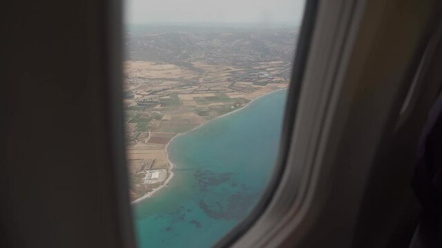 Traveling by plane to island of Cyprus after opening borders quarantine covid 19. View of Cyprus through window of aircraft upon arrival at pafos airport. Top view mediterranean sea porthole airplane