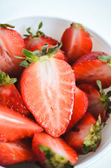 Fresh red strawberries with leaves on a white background close up. Strawberries in a white glass bowl.