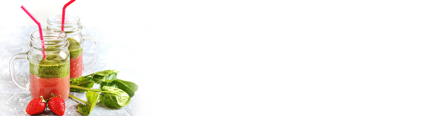 layered smoothies made of strawberries and spinach in a trendy jar with a handle. Next to fresh strawberries and juicy spinach leaves. organic food.