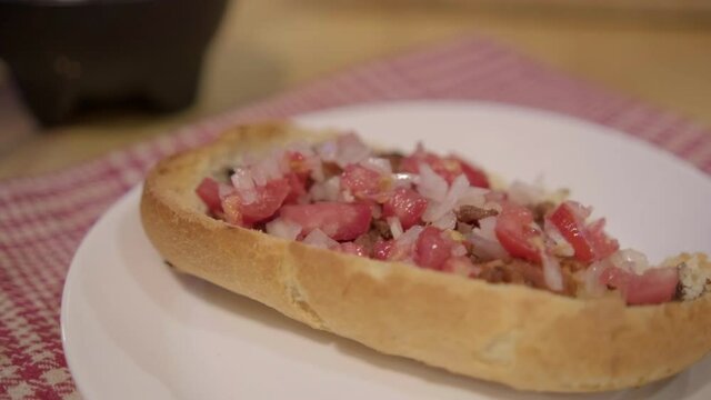Traditional Mexican mollete on a plate above white and red checkered napkin