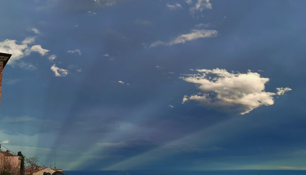 Cielo fantastico all&rsquo;imbrunire con nuvole su scie di luce che partono dal mare come comete