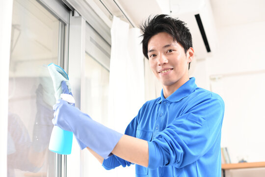 窓拭きをする清掃業のの作業服の若い男性