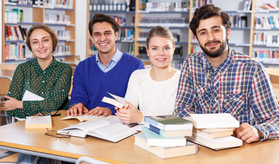 Friendly group of students preparing together for exam in modern university library .