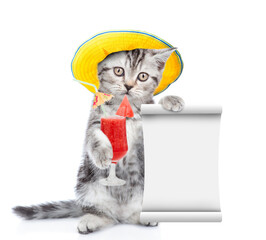 Cute kitten wearing tiny summer hat holds tropic cocktail and shows empty list. isolated on white background