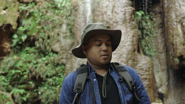 The young explorer traveled among the many rocks.He look around. The hikers are traveling in the rain forest with beautiful nature. Young Asians go on a journey through the forest.