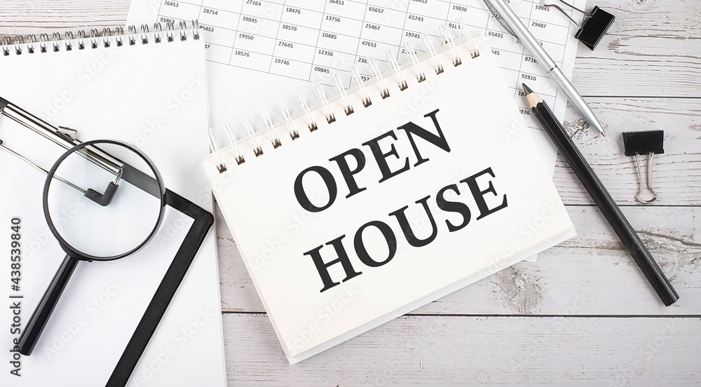 Poster notepad with text open house with a pen,office tools and graphs on the desktop.
