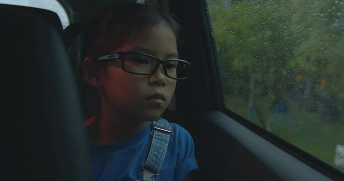 Asian Child Girl Is Looking Out From Car Window In The Rainy Day