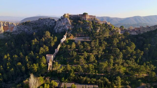 The castle of J&aacute;tiva from a spectacular aerial view at sunset surrounded by nature and an ancient city.