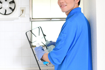 Naklejka na ściany i meble ガスコンロの掃除をする清掃業の作業服の若い男性