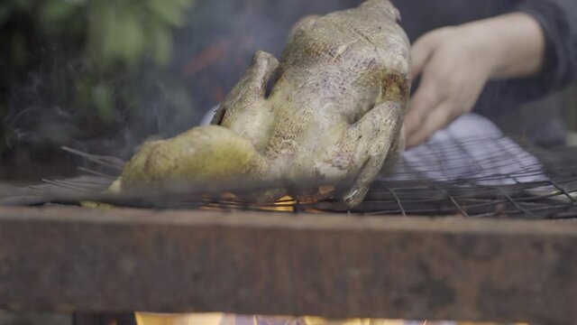 Chef sears chicken carcass on open chulha fire prior to butchering it