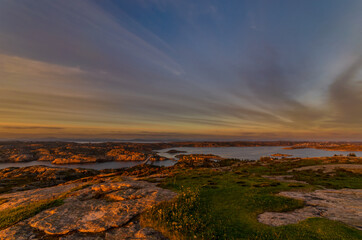 A curved bridge over a Norwegian fjord during a colorful sunset.