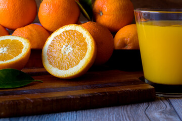 Fresh orange fruit whole and sliced on a cutting board and glass of fresh orange juice cocktail