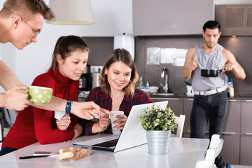 Young cheerful positive smiling travelers with laptop planning tourist itinerary during breakfast...