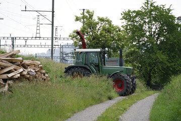 Tractor near railway tracks at rainy day at summer time. Photo taken June 9th, 2021, Eglisau, Switzerland.
