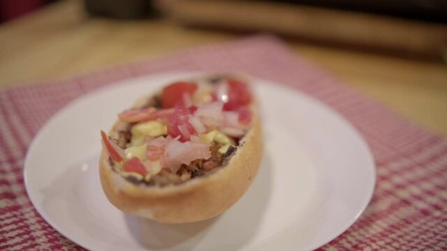 Traditional Mexican mollete on a plate above white and red checkered napkin