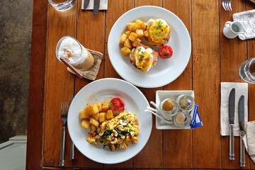 Scrambled and eggs benedict served with grilled potatoes and coffee