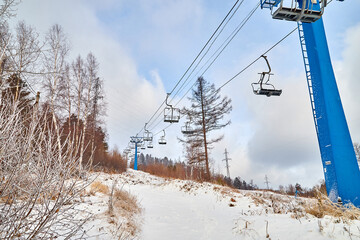 Cableway or cablecar with cabanas goes up in the mountains in winter day and blue sky on background
