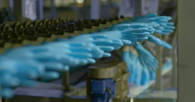Rubber medical gloves rotate on molds along a conveyor belt, factory production of rubber products. Modern equipment for the production of silicone gloves, conveyor belt. 4k, ProRes