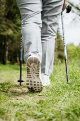 Woman walking in nature. Close-up of boots, trekking poles for outdoor Nordic walking. Active...
