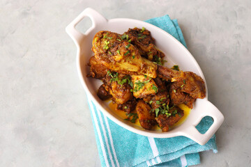 Chicken Tava fry or dry fry. A popular Indian Tawa Murg served in a white plate. Chicken masala garnished with coriander and spices. Copy space. Chicken Tangdi kabab.
