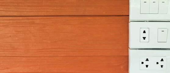 Set of electrical plugs and switches mounted on the wall, wooden house background