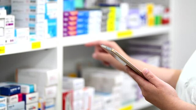 Pharmacist holding computer tablet Inspecting medicine stock in pharmacy drugstore.