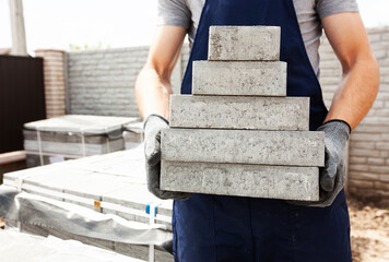 The worker picked up the stack with paving stones
