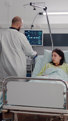 Afro american nurse arrange sick woman bed during medical recovery working in hospital ward, Practitioner doctor checking patient monitoring disease diagnosis explaining rehabilitation treatment