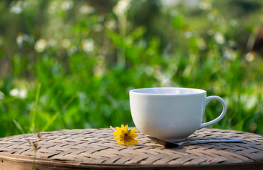 white ceramic cup of black coffee with nice smoke above a cup and morning sunlight, natural...