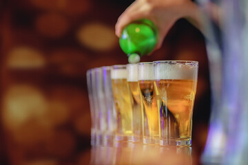 Soft Light And Smooth Focus,The young woman poured beer in an Arrange of beer glasses on the bar counter to serve customers who were celebrating success. The idea of drinking alcohol or beer to relax.