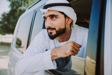 Handsome man with uae traditional outfit driving in Dubai. Middle eastern man with kandura in the...
