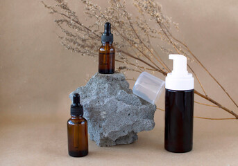 Brown glass bottles of cosmetics on stone, on beige paper background. Natural Organic Spa Beauty Beauty Concept Front View Layout