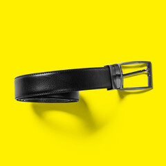 Top up up view black leather belt isolated on yellow background. suitable for your design project.