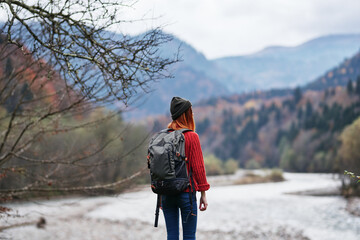 happy woman with backpack rest in the mountains near the river on nature autumn landscape fresh air